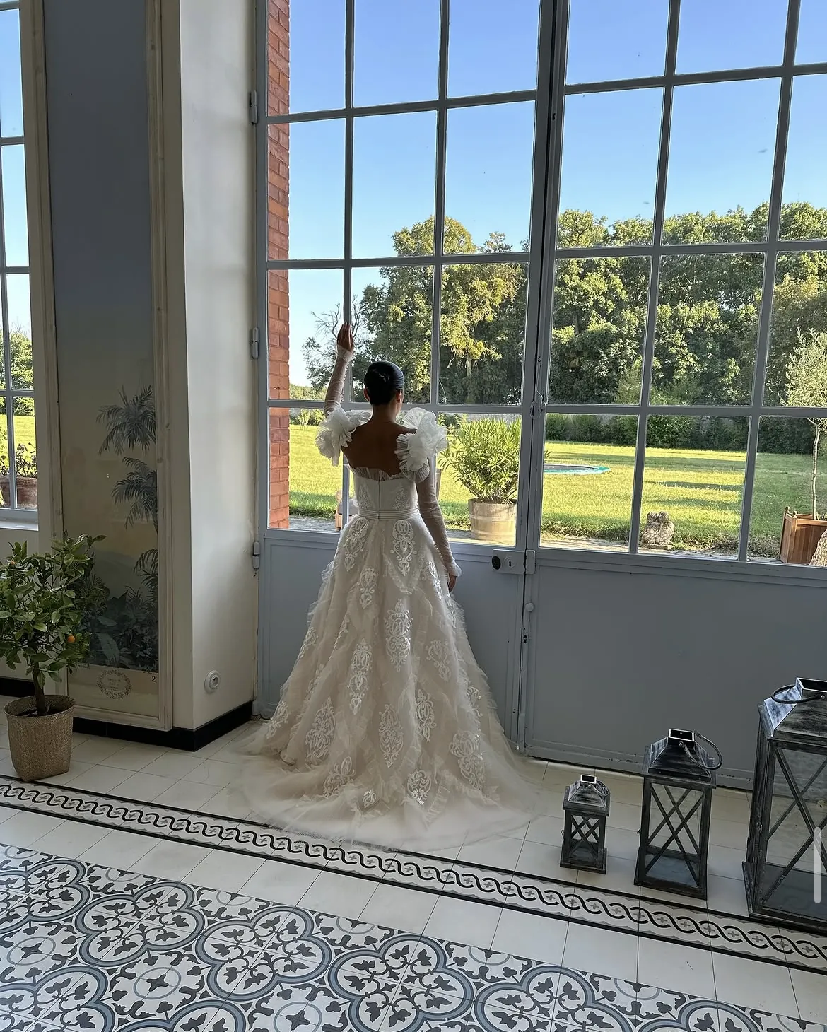 La mariée de dos devant la verrière du Château Barthélemy
